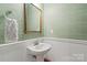 Powder room features a pedestal sink, framed mirror, and green wall-covering at 1354 Galloway Rd, Charlotte, NC 28262