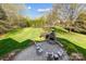 Expansive backyard featuring a stone fireplace, patio, lush lawn, and mature trees at 1404 Churchill Downs Dr, Waxhaw, NC 28173