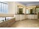 Bright bathroom with dual vanities, granite counters, decorative mirrors, and a soaking tub at 1404 Churchill Downs Dr, Waxhaw, NC 28173