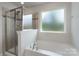 Bright bathroom showcasing a glass shower and a separate soaking tub beneath a window at 16803 Cozy Cove Rd, Charlotte, NC 28278