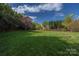 Expansive backyard with lush green grass, a wooden fence, and mature trees at 17309 Knoxwood Dr, Huntersville, NC 28078