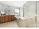 Bright bathroom with a soaking tub, glass shower, and a round mirror above the vanity at 17309 Knoxwood Dr, Huntersville, NC 28078