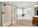 Bright bathroom featuring a glass enclosed shower and a soaking tub under a window at 2004 Ptarmigan Ct, Waxhaw, NC 28173