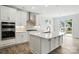 Open concept kitchen with white cabinets, island, stainless appliances, and backyard view at 2017 Embassy Ct # 51, Charlotte, NC 28213
