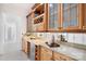 A bar area featuring wooden cabinets, wine storage, a mirrored backsplash, and granite countertops at 5001 Oxfordshire Rd, Waxhaw, NC 28173