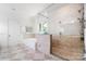 A bathroom featuring a bathtub and glass-walled shower with beige tiled surround at 5001 Oxfordshire Rd, Waxhaw, NC 28173
