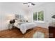 Bright bedroom featuring hardwood floors, a ceiling fan, and two decorative pieces hanging above the headboard at 5001 Oxfordshire Rd, Waxhaw, NC 28173
