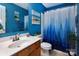 Well-lit bathroom with blue walls, shower with curtain and natural wood vanity at 5127 Fernhill Dr, Charlotte, NC 28217