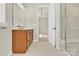 This is a bathroom featuring a wooden vanity, a tiled walk-in shower, and a doorway to another room at 5850 Strathmore Ct, Charlotte, NC 28215