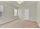 A standard bedroom with tan colored walls and carpet, a window and a door at 5850 Strathmore Ct, Charlotte, NC 28215