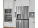 Modern stainless steel refrigerator and built-in microwave and oven are featured with white cabinetry at 5850 Strathmore Ct, Charlotte, NC 28215