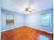 A well-lit bedroom with hardwood floors, two windows, and a ceiling fan at 6430 Farmingdale Dr, Charlotte, NC 28212