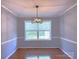 Bright dining room featuring hardwood floors, wainscoting, and a modern chandelier fixture at 6430 Farmingdale Dr, Charlotte, NC 28212