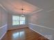 Charming dining room featuring hardwood floors, modern light fixture, and large bright window at 6430 Farmingdale Dr, Charlotte, NC 28212