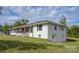 View of a white single story home with a cozy front porch and a lush green yard at 6599 Mcintosh Rd, Stanley, NC 28164