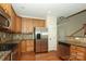 Kitchen featuring stainless steel appliances, granite countertops, and wood cabinets, leading to staircase at 729 Naramore St, Davidson, NC 28036