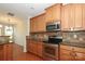 Fully-equipped kitchen with stainless steel appliances, wood cabinets, and granite countertops at 729 Naramore St, Davidson, NC 28036