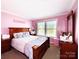 Charming bedroom with soft pink walls, plush bedding, and a large window offering plenty of light at 7928 Ponderosa Pine Ln, Charlotte, NC 28215