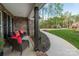 Inviting covered front porch with outdoor seating and red pillows, creating a warm welcome to the brick home at 8209 Bella Vista Ct, Charlotte, NC 28216
