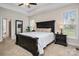 Main bedroom with a large dark wood bed frame, tray ceiling, side tables with lamps, and multiple windows at 8209 Bella Vista Ct, Charlotte, NC 28216