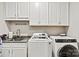 Well-lit laundry room with granite countertops, stainless sink, modern washer, and dryer with white cabinetry at 8718 Festival Way, Charlotte, NC 28215