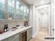Butler's pantry with marble countertops, glass-front cabinets, wine cooler and access to the hallway at 8805 Wingard Dr, Waxhaw, NC 28173