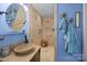 Blue bathroom with travertine-tiled shower, wood sink, and stylish decorative accents at 10308 Garrett Grigg Rd, Charlotte, NC 28262