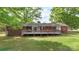 Backyard view of a brick home with a deck, surrounded by green grass and mature trees at 1099 S Potter Rd, Lancaster, SC 29720