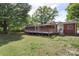 A large backyard with a brick home and wood deck surrounded by trees at 1099 S Potter Rd, Lancaster, SC 29720