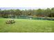 A tranquil backyard with a pond and lush green grass and a wooden picnic table for outdoor dining at 1151 Trull Hinson Rd, Wingate, NC 28174