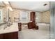 This bathroom features a makeup vanity, large soaking tub, cherry wood cabinets, and decorative wallpaper at 1151 Trull Hinson Rd, Wingate, NC 28174