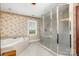 Bathroom boasts a large jetted tub, glass shower, tile floor, large window, and decorative wallpaper at 1151 Trull Hinson Rd, Wingate, NC 28174