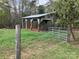 Rustic horse shelter with metal roof and fencing in a grassy field with scattered trees at 13079 Philadelphia Church Rd, Oakboro, NC 28129