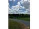Gravel driveway leading to a gated property with green pastures and a cloudy sky at 13079 Philadelphia Church Rd, Oakboro, NC 28129