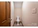 This bathroom has a white toilet, beige walls, and a wood door for easy access at 1478 Smith Farm Rd, Lincolnton, NC 28092