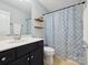 Bright bathroom features a vanity with a sink, decorative floating shelves, and a shower with a stylish curtain at 15643 Canmore St, Charlotte, NC 28277