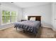 A cozy bedroom with a wooden headboard, plush carpeting, and natural light from a nearby window at 15643 Canmore St, Charlotte, NC 28277