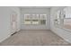 Light-filled bedroom with plush carpet, access to a door, and multiple windows for natural light at 224 Old Harbor Dr, Mount Gilead, NC 27306