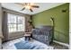 Stylish Bedroom featuring a crib, rocking chair, area rug, and a large window at 239 Bradford Glyn Dr, Mooresville, NC 28115
