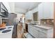 Galley kitchen featuring white cabinets, stainless steel appliances, tile backsplash, and wood flooring at 239 Bradford Glyn Dr, Mooresville, NC 28115