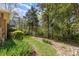 Grassy backyard with mature trees, shrubs, and a wooden fence at 481 Patriot Ne Ct, Concord, NC 28025