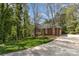 A brick home with a long driveway surrounded by lush greenery and trees on a sunny day at 481 Patriot Ne Ct, Concord, NC 28025
