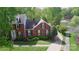 An aerial view of a traditional brick home showcasing its well-maintained yard and a serene pond nearby at 5043 Hickory Lake Ln, Matthews, NC 28105