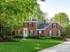 Charming brick home with lush green lawn, mature trees, and manicured landscaping for great curb appeal at 5043 Hickory Lake Ln, Matthews, NC 28105