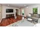Living room with hardwood floors, large TV, a gray sofa and view into other rooms of the house at 5043 Hickory Lake Ln, Matthews, NC 28105