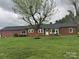 Charming brick home featuring a lush front yard, a mature tree, and a cozy front porch with inviting seating at 5373 Nc Hwy 16 N Hwy, Taylorsville, NC 28681