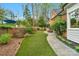 Manicured backyard featuring lush artificial turf, garden beds, and a charming brick-lined pathway at 5750 Hemby Rd, Matthews, NC 28104