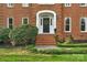 Close-up of the brick home's entry featuring decorative wreath, white trim, and well-kept landscaping at 5750 Hemby Rd, Matthews, NC 28104