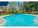 Sparkling blue swimming pool surrounded by lush greenery and patio space with plenty of room for entertaining at 5750 Hemby Rd, Matthews, NC 28104