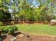 Large, well-maintained backyard featuring lush green grass, a wooden fence, and mature trees at 7822 Noland Woods Dr, Charlotte, NC 28277